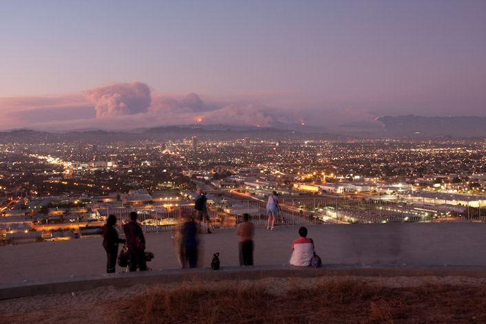 The fire is revealed at dusk as onlookers gaze and snap photos