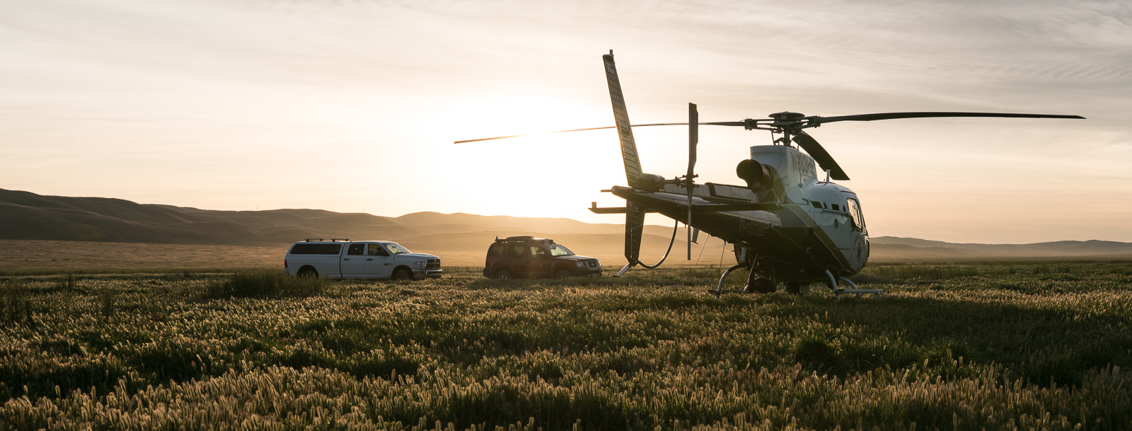 two cars and a helicopter at sunset